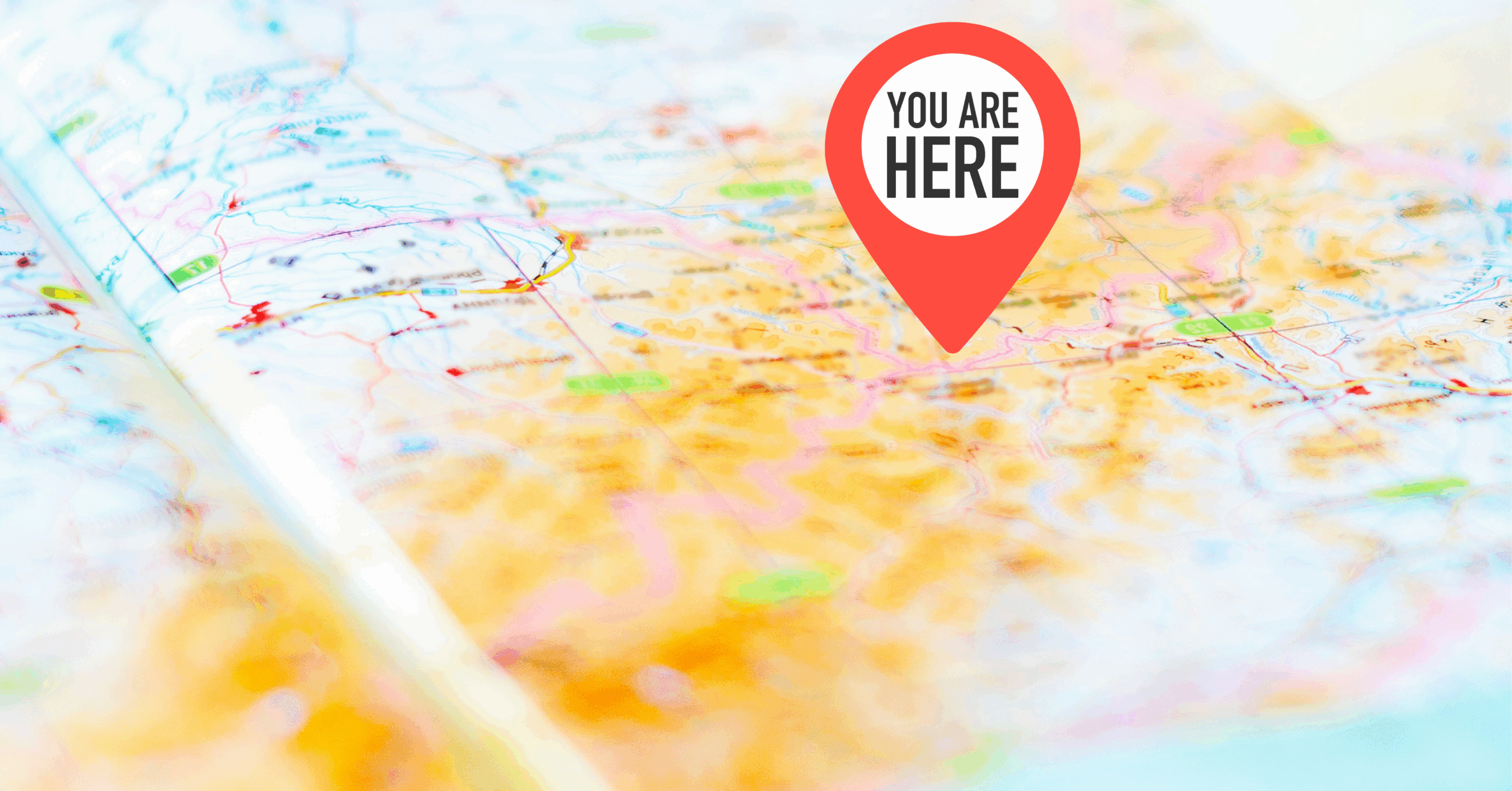 A map with a red location pin that reads "You Are Here," representing the idea of benchmarking your current status or data.