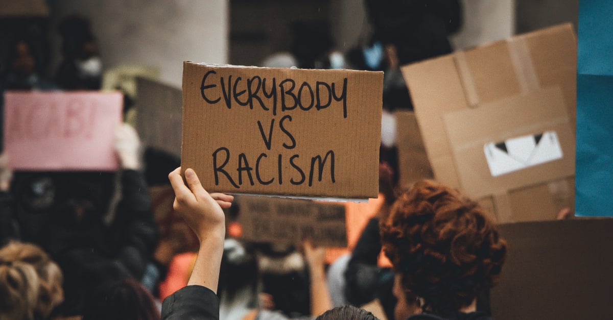 Photograph of placard being held up in a crowd with the message: EVERYBODY VS RACISM